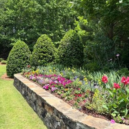 Stone retaining wall with colorful flower bed landscaping installed by In the Roots in Chelsea, Alabama